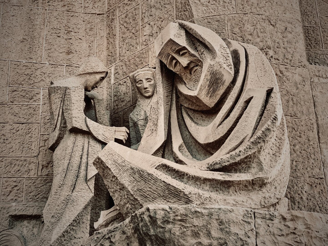 Tres figuras de piedra con mantos angulosos componen un relieve escultórico en la fachada de la Sagrada Familia de Barcelona.