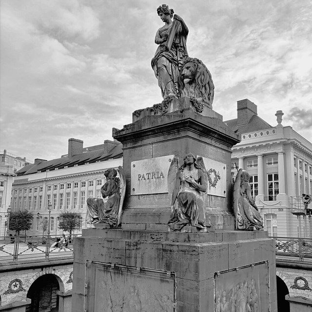 Un monumento de Bruselas reúne figuras alegóricas, un león y la inscripción «Patria» sobre un pedestal de piedra.