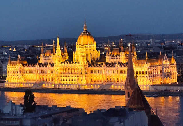 El Parlamento de Budapest brilla al anochecer y refleja sus luces doradas sobre el Danubio.