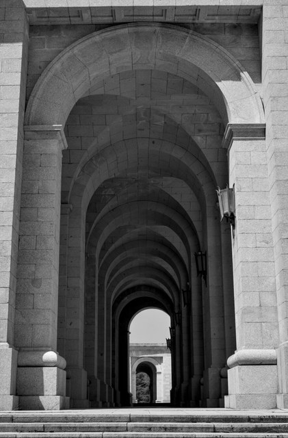 Arcos de granito de El Escorial se repiten en profundidad hasta una pequeña abertura iluminada.