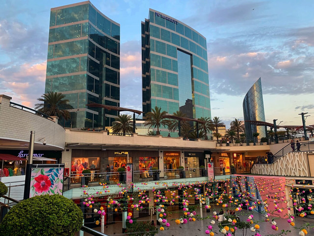 Torres acristaladas del JW Marriott se elevan sobre un centro comercial decorado con flores en Lima.