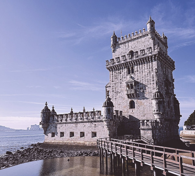 La Torre de Belém se alza junto al río, conectada a tierra por una pasarela de madera.