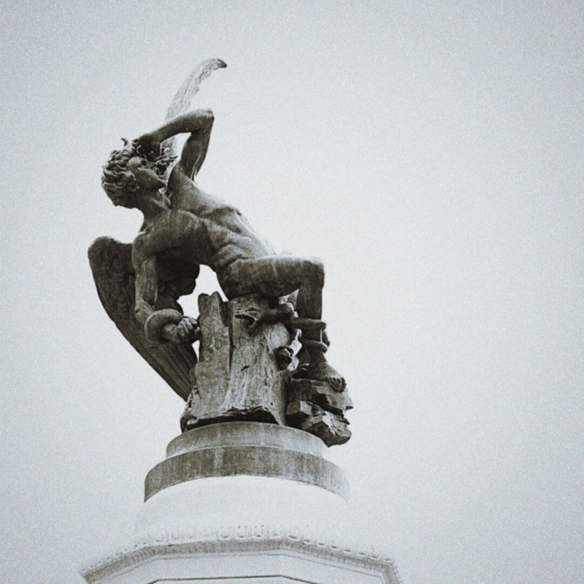 El Ángel Caído de Madrid alza un brazo mientras una serpiente rodea su cuerpo sobre un pedestal.