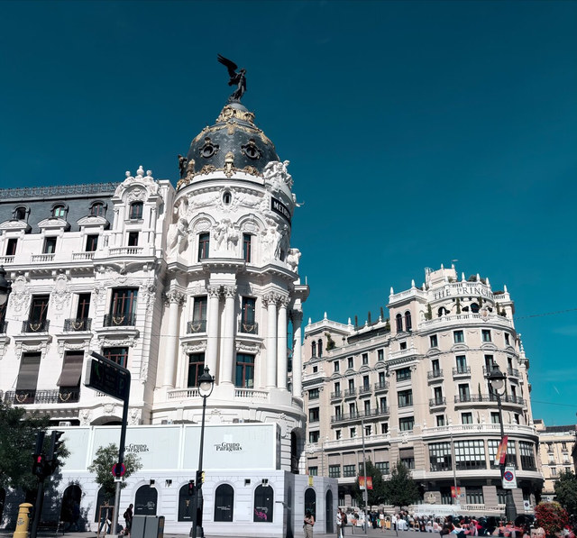 El edificio Metrópolis exhibe su cúpula negra y dorada coronada por una figura alada bajo el cielo azul.