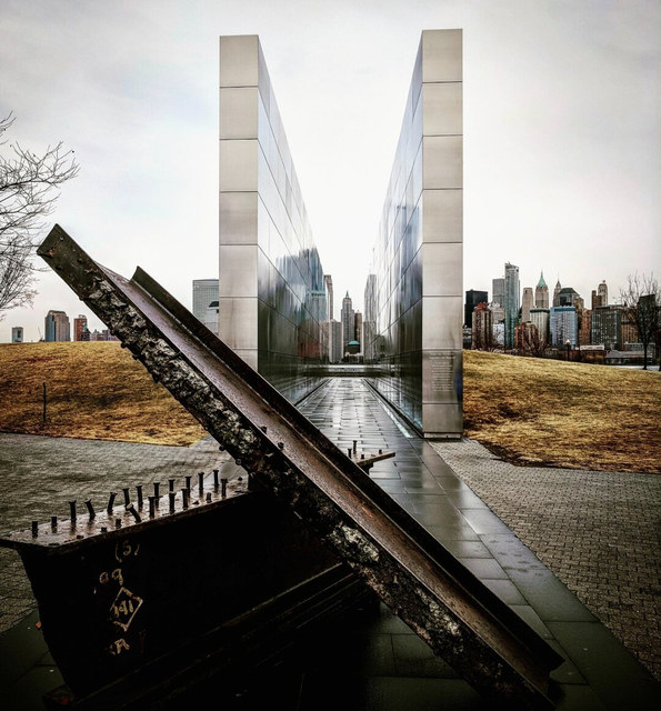 Una viga oxidada del World Trade Center cruza ante dos muros metálicos que enmarcan Manhattan.