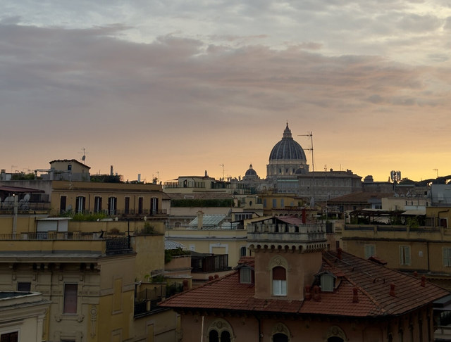 Tejados, terrazas y antenas de Roma rodean la cúpula de San Pedro durante un atardecer dorado.
