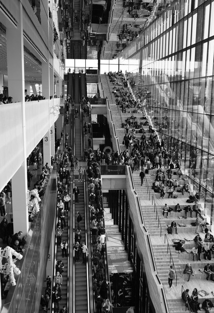 Un atrio acristalado de Seattle concentra multitudes en escaleras mecánicas, graderíos y pasarelas distribuidas en varios niveles.
