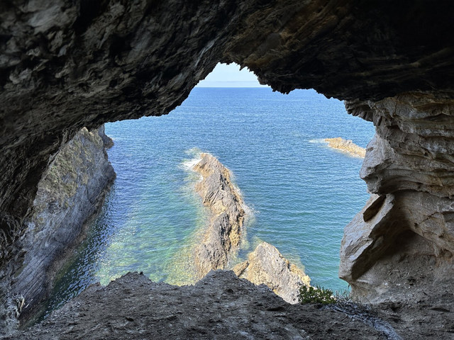 Una abertura rocosa enmarca el mar azul y varias crestas de piedra junto a la costa de Viveiro.