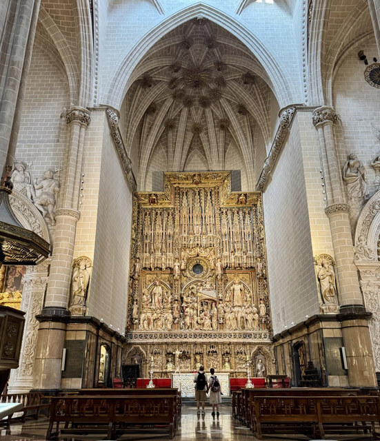 Dos visitantes observan un gran retablo dorado bajo las bóvedas góticas de un templo de Zaragoza.